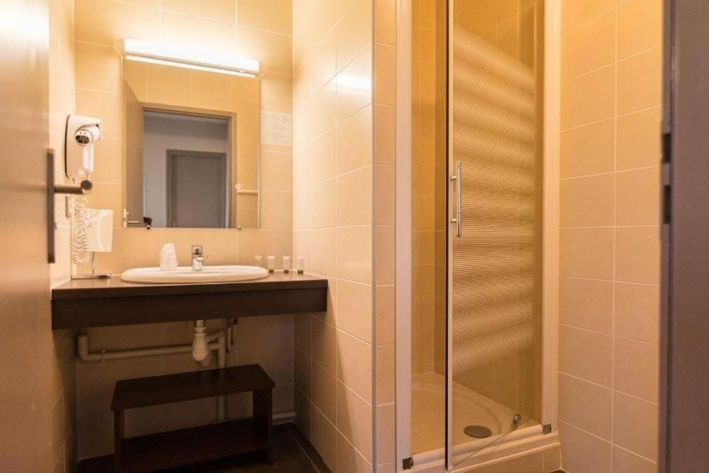 Un baño con lavamanos, espejo y ducha con mampara de vidrio.