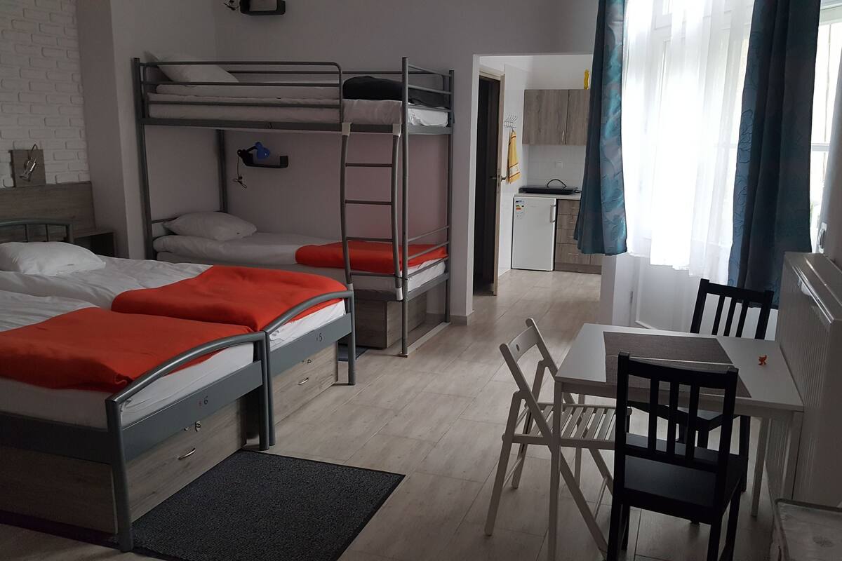 A dormitory room with bunk beds, a desk, and a chair.