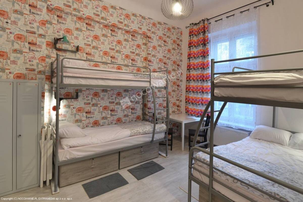 A dormitory room with bunk beds, a desk, and lockers.