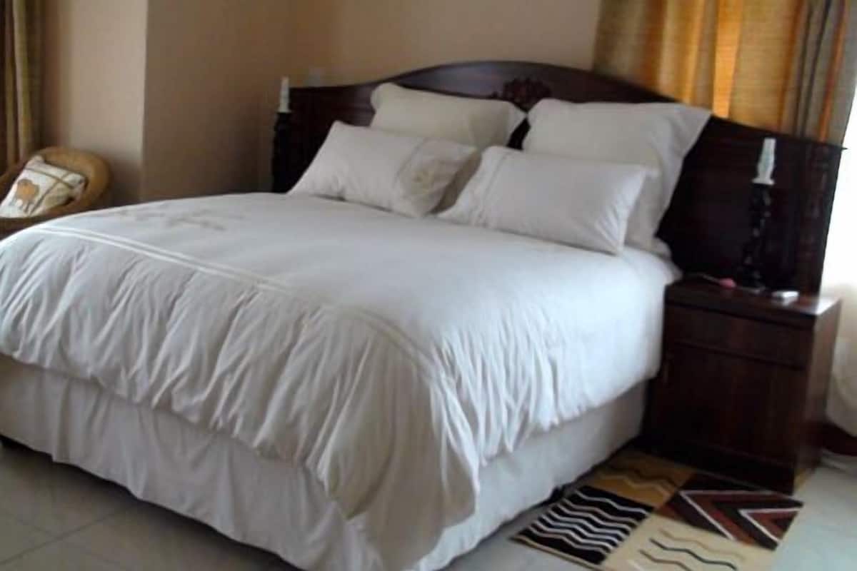 Cama bem arrumada com lençóis brancos em quarto de hotel.