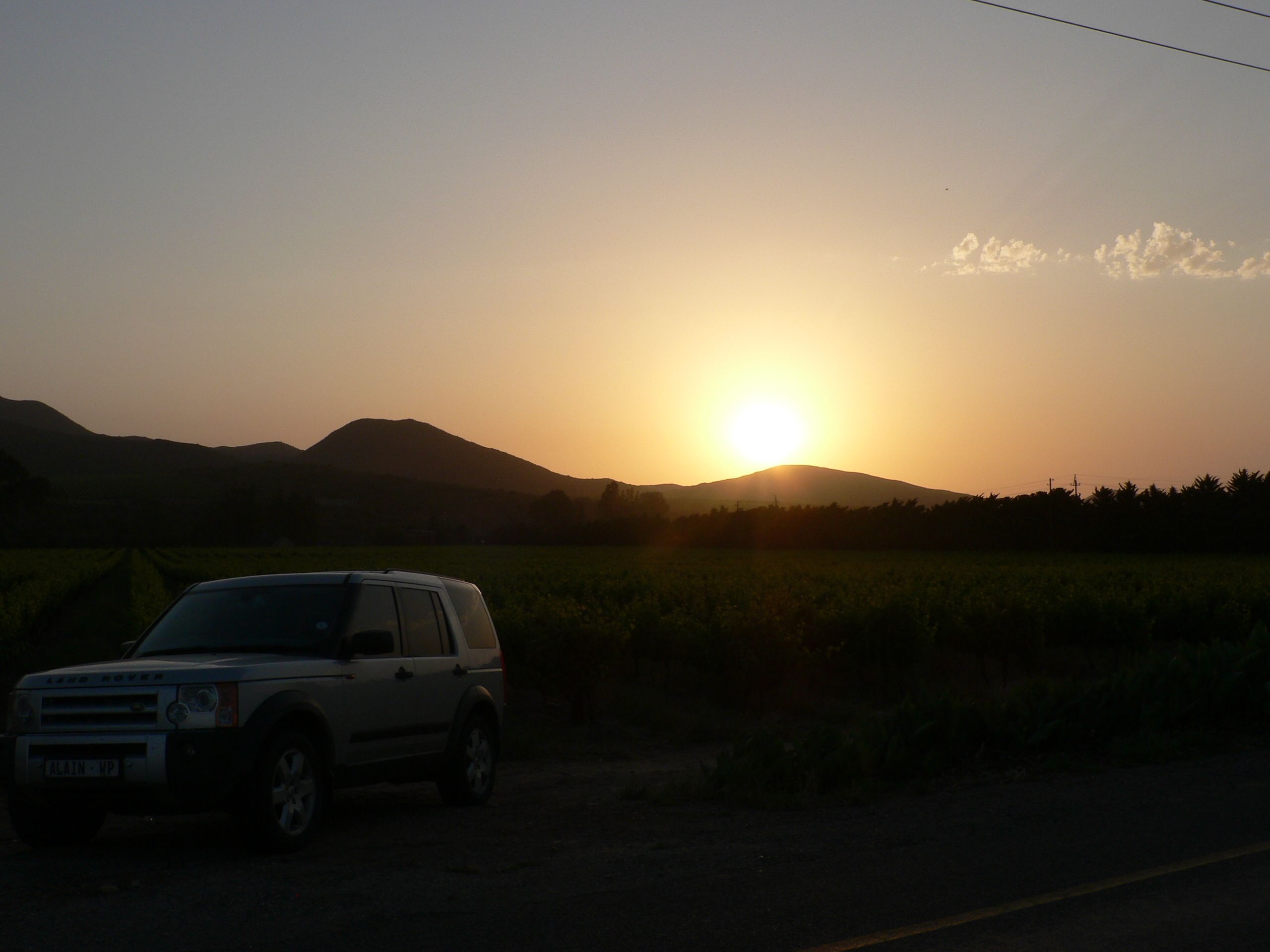 A vehicle parked on a road with a sunset in the background.