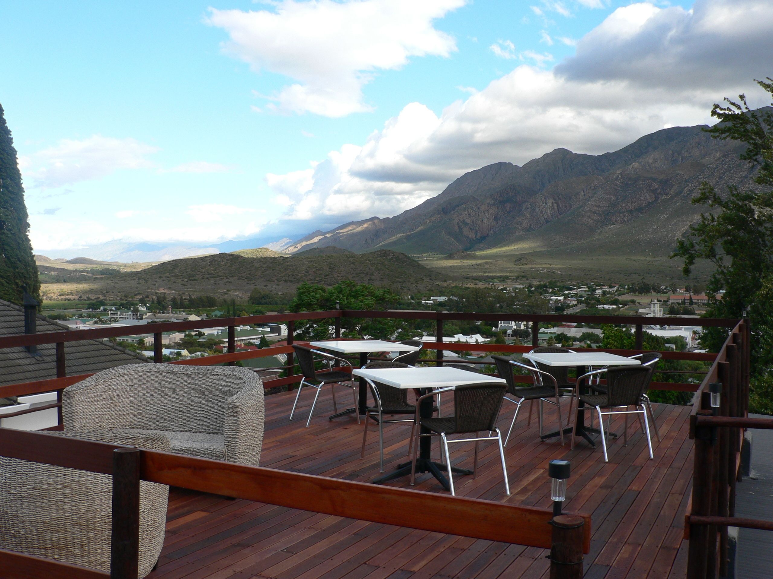 A deck with tables and chairs overlooking a mountainous landscape.