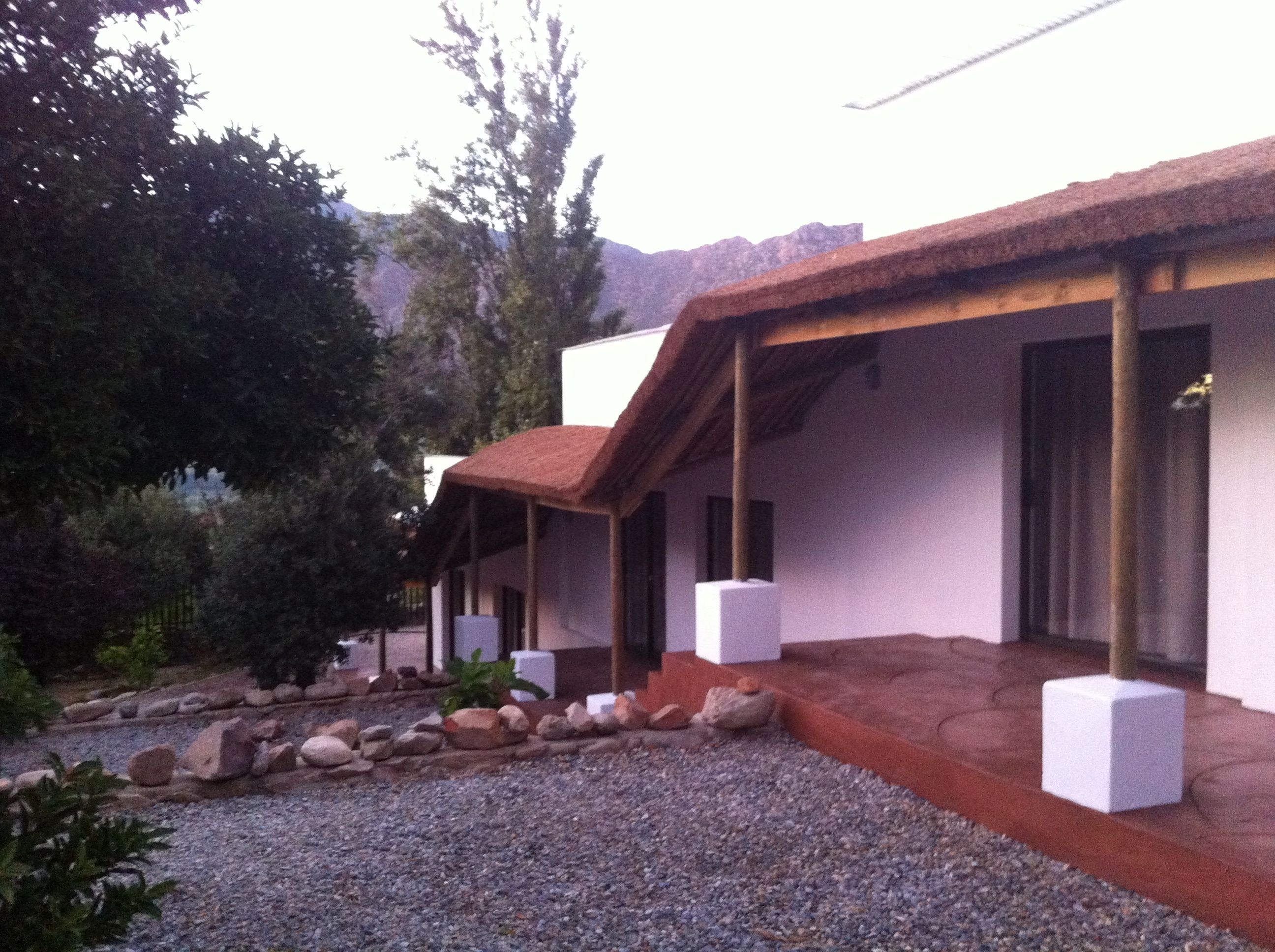 A building with a covered patio area, white walls, and a gravel ground.