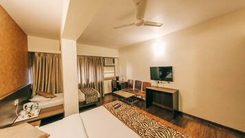 A hotel room with a bed, a desk, a chair, a television, and a ceiling fan.