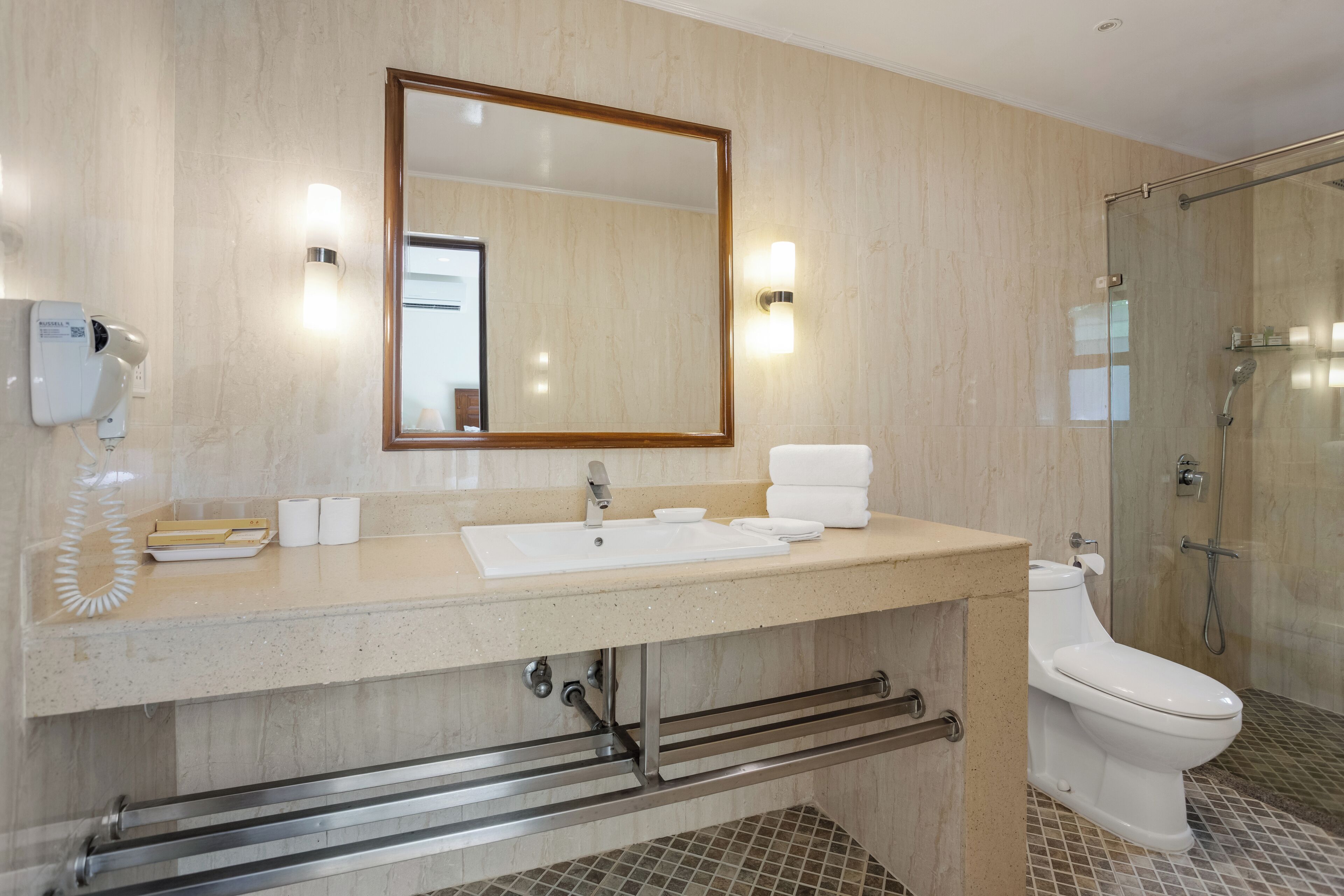Un baño moderno con un espejo grande, un lavabo, un inodoro y una ducha con mampara de vidrio.