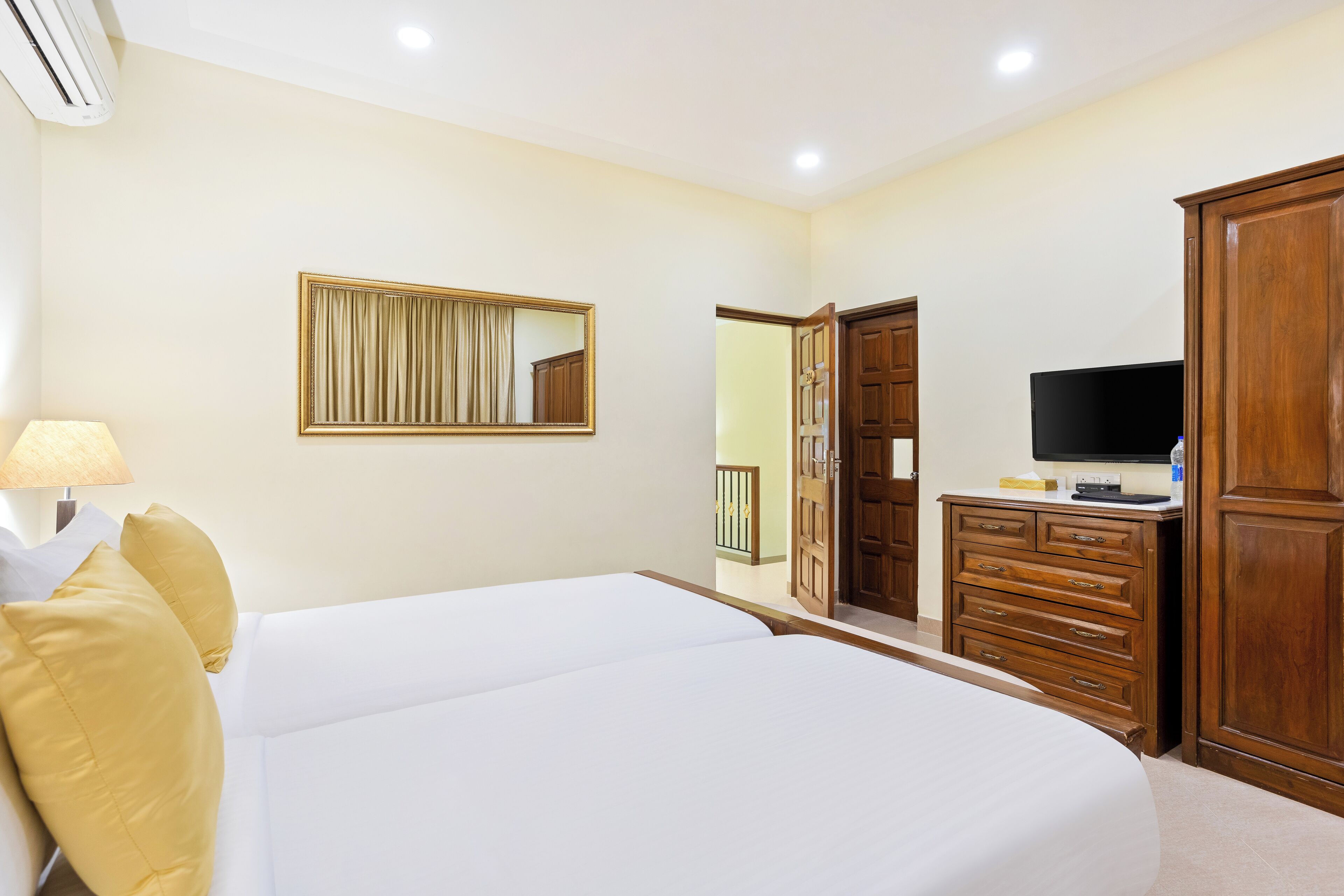 A hotel room with a large bed, a TV, a dresser, and a mirror.
