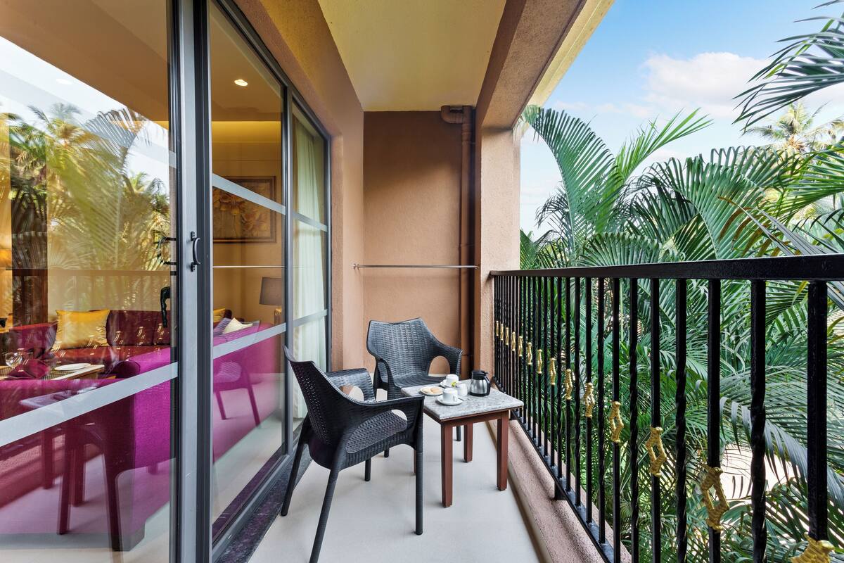 A balcony with two wicker chairs, a small table, and a sofa with cushions.