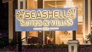Letrero de Seashell Suites & Villas en Goa, con un logotipo destacado y texto iluminado.