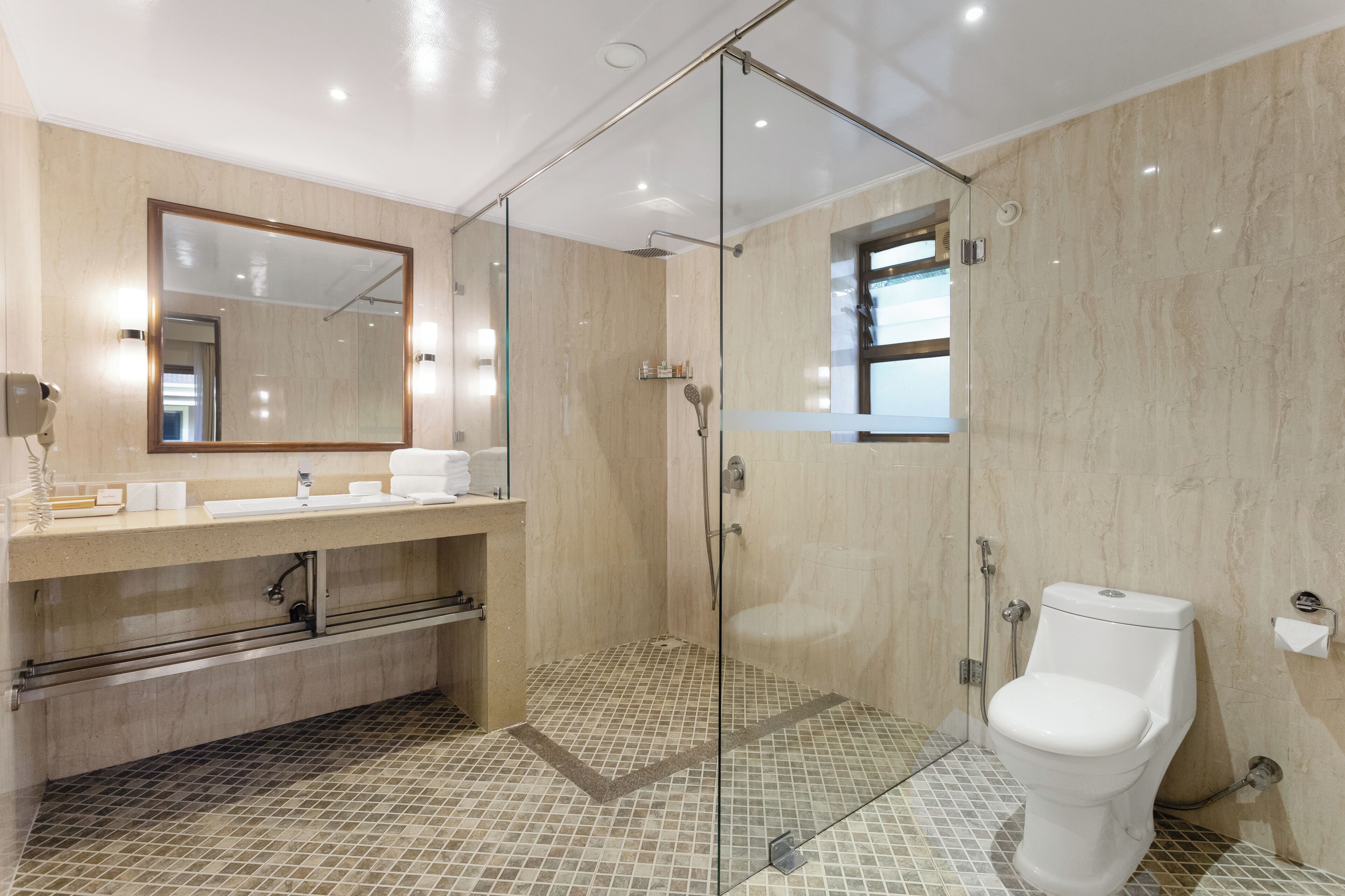 Une salle de bain moderne avec une douche à parois de verre, un grand miroir et des toilettes.