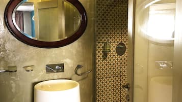 Une salle de bain avec un miroir rond, un lavabo, un porte-serviettes et un mur décoré d’un motif.