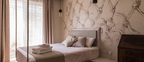 Une chambre avec un grand lit, un plancher en bois, un luminaire au plafond et une fresque murale.
