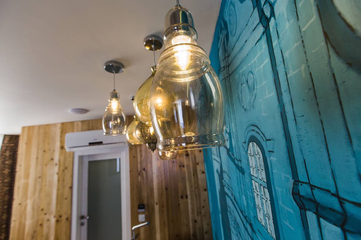 Quarto com paredes de madeira e uma porta, com luminária pendente e um mural na parede.