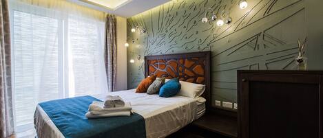 Una habitación de hotel moderna con una cama grande, una mesita de noche y un cabecero decorativo.