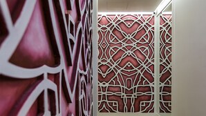 Un couloir aux murs décorés de motifs et dont le sol est recouvert de moquette.