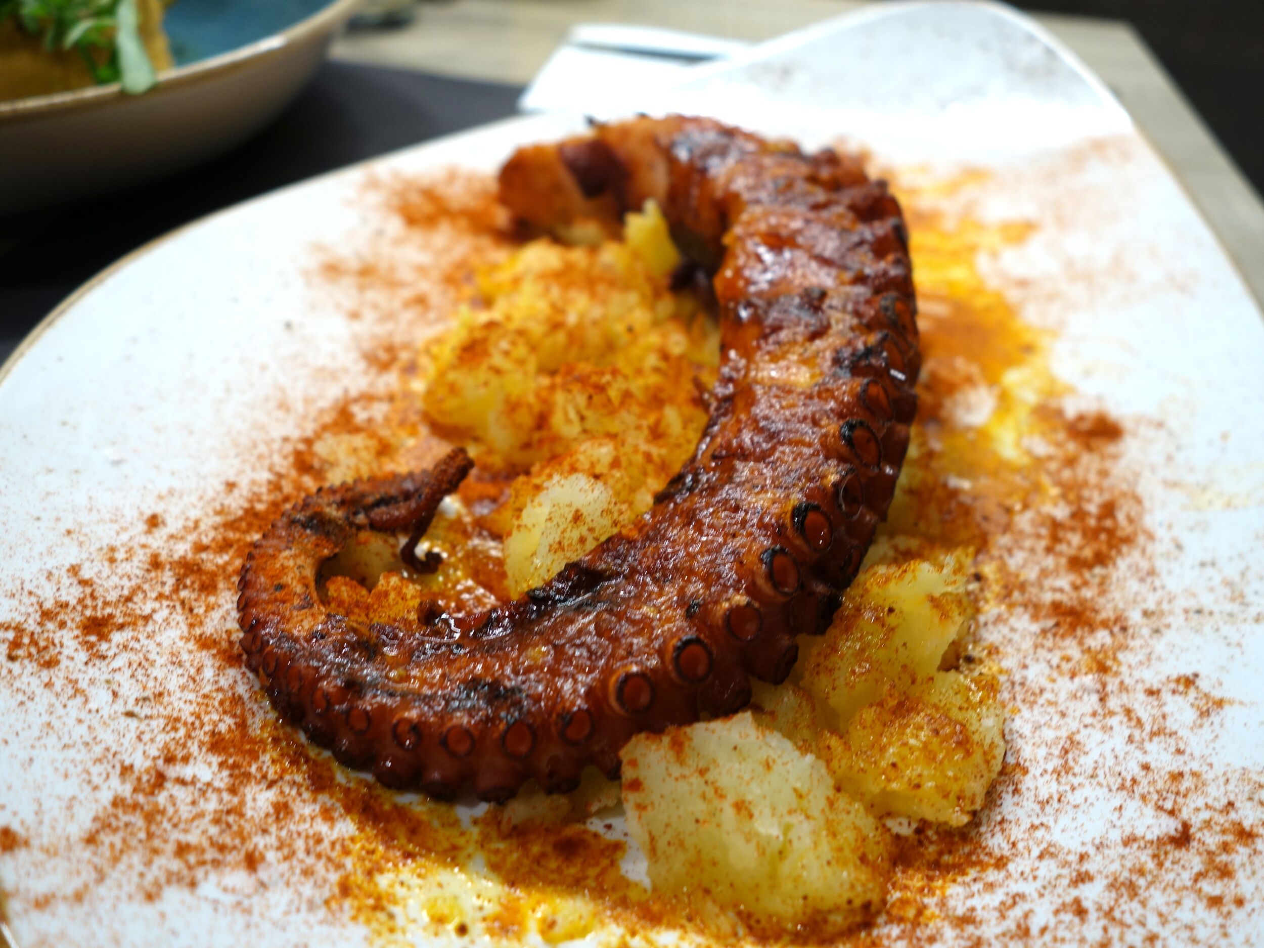 Une assiette de poulpe grillé et de pommes de terre, assaisonnée d’épices.