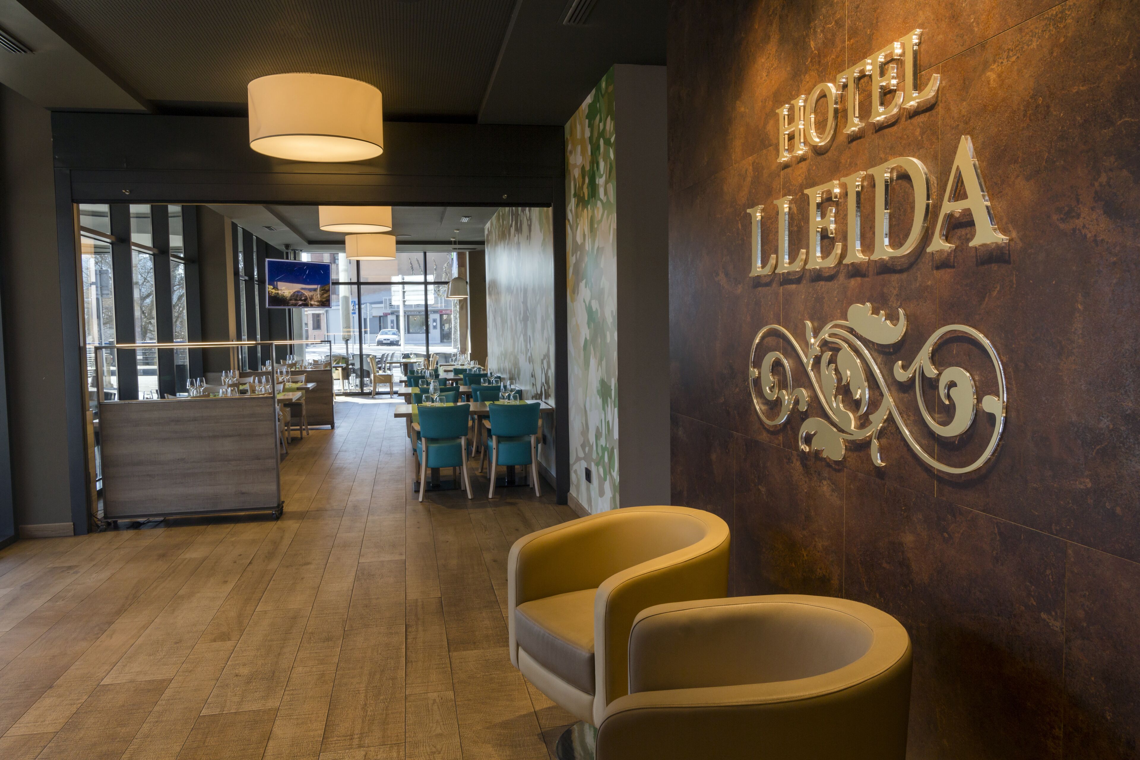 A hotel lobby with a reception desk, seating area, and a wall with the hotel name.
