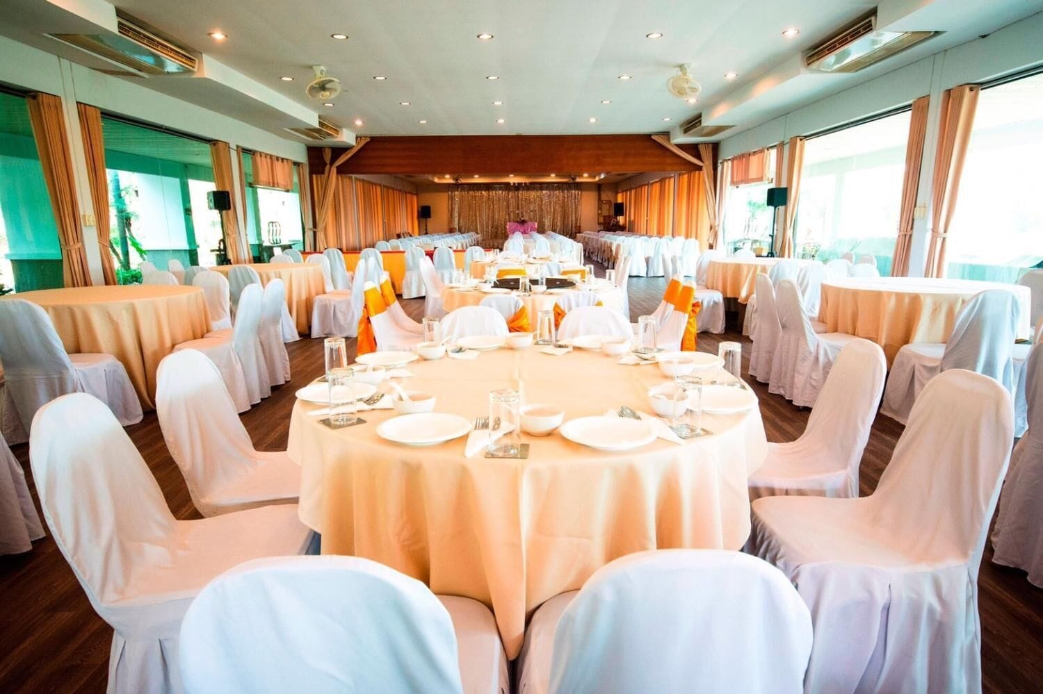 A conference room with round tables and white chairs, equipped with nameplates and table settings.