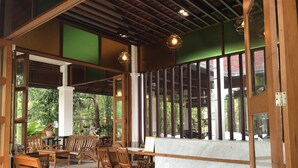 An indoor seating area with wooden furniture and large windows. - Tak Andaman Resort & Hotel (Tak)