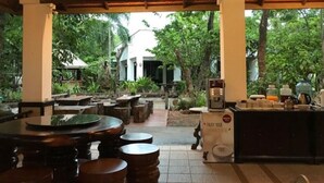 An outdoor seating area with wooden tables and chairs, a coffee machine, and a sign welcoming guests to the Andaman Resort. - Tak Andaman Resort & Hotel (Tak)
