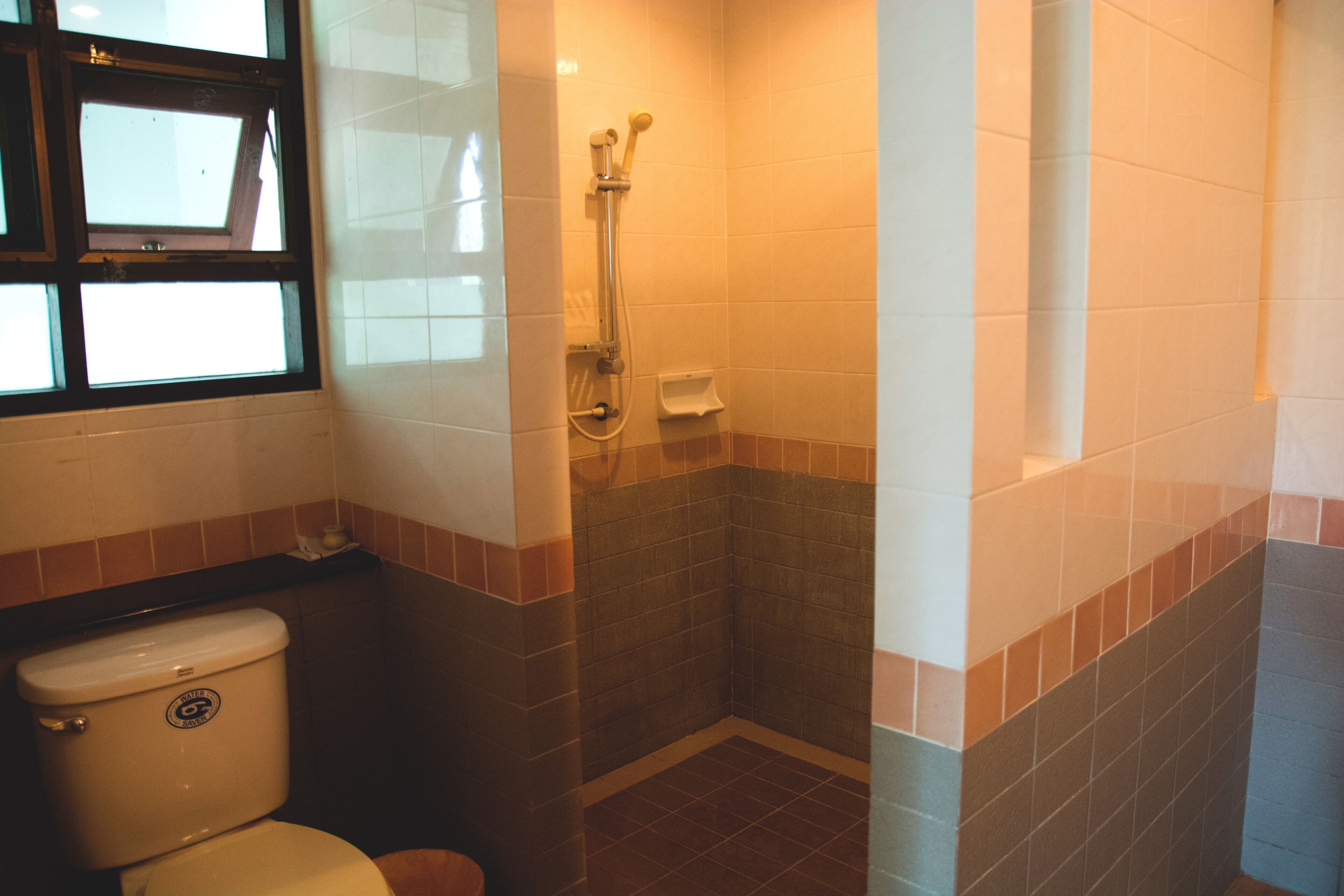 A bathroom with a toilet, shower, and tiled walls.