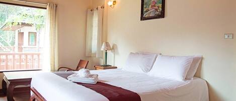 A hotel room with a large bed, a wooden desk, a chair, a lamp, and a picture on the wall.