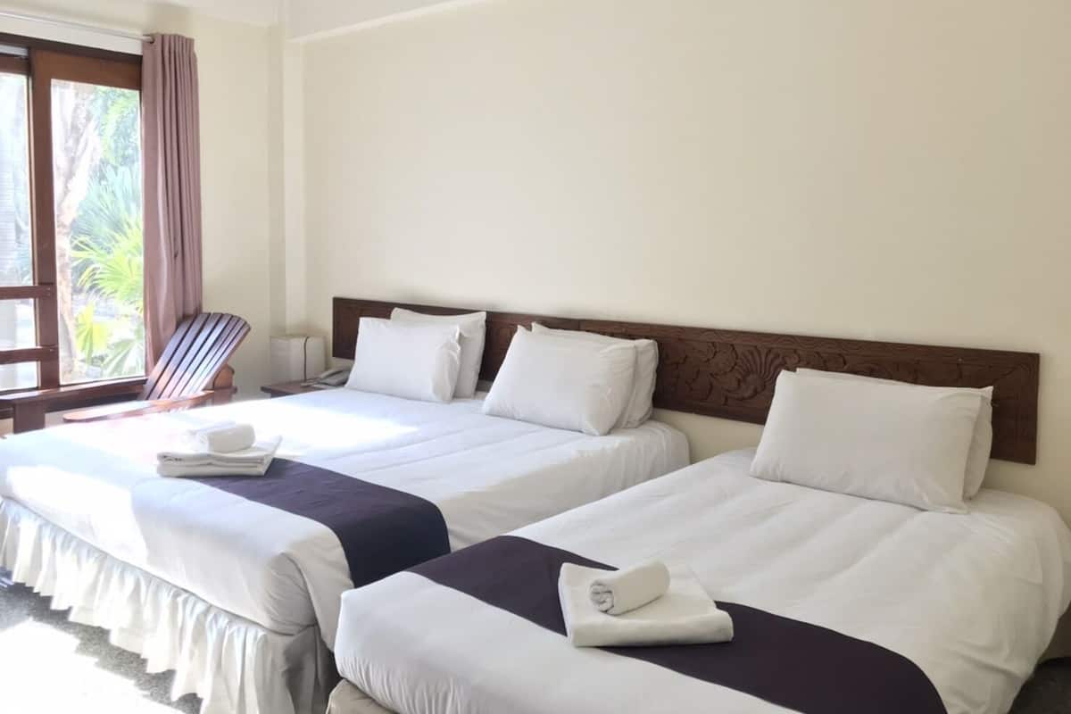 A hotel room with two beds, each with white linens and dark headboards.