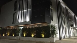 Un edificio moderno con iluminación vertical y un área ajardinada con plantas.