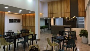 Un espacio interior amplio con varias mesas y sillas para comer, un ventilador de techo e iluminación empotrada.