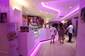 A modern cafe interior with a central counter, seating area, and a display case. - Palma D'Oro (Bagnara Calabra)