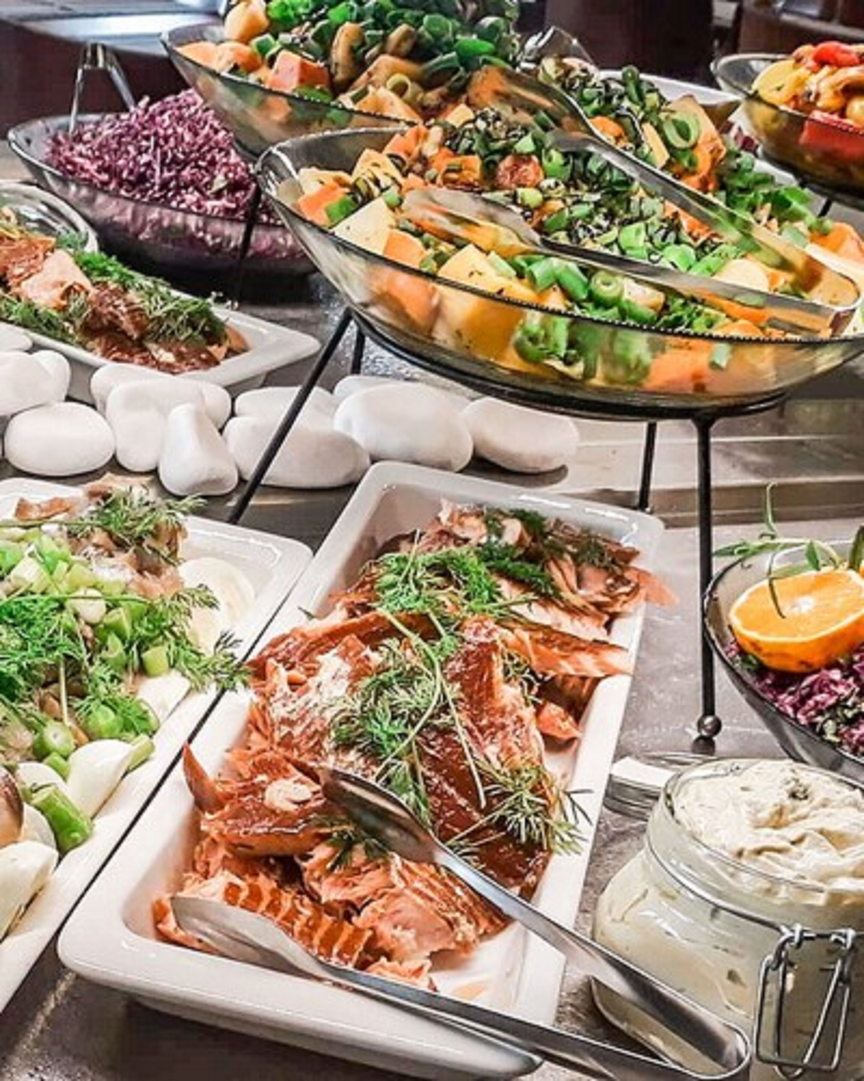 Un bufé con diversos platos, incluyendo ensaladas, carnes y mariscos.