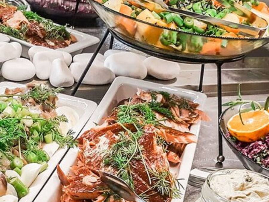 Un bufé con diversos platos, incluyendo ensaladas, carnes y mariscos.