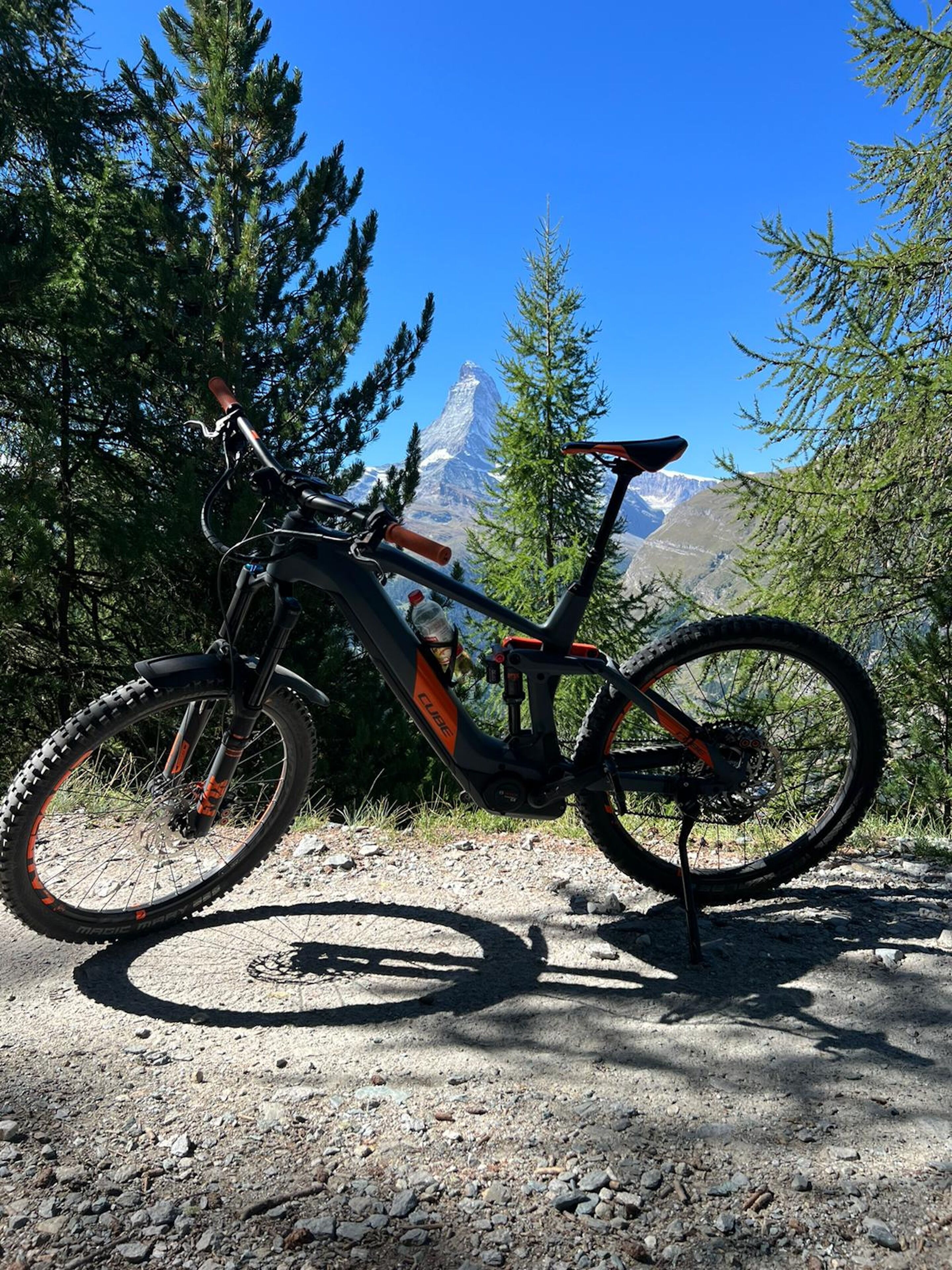 En mountainbike parkerad på en grusväg, med en vacker bergsvy i bakgrunden.