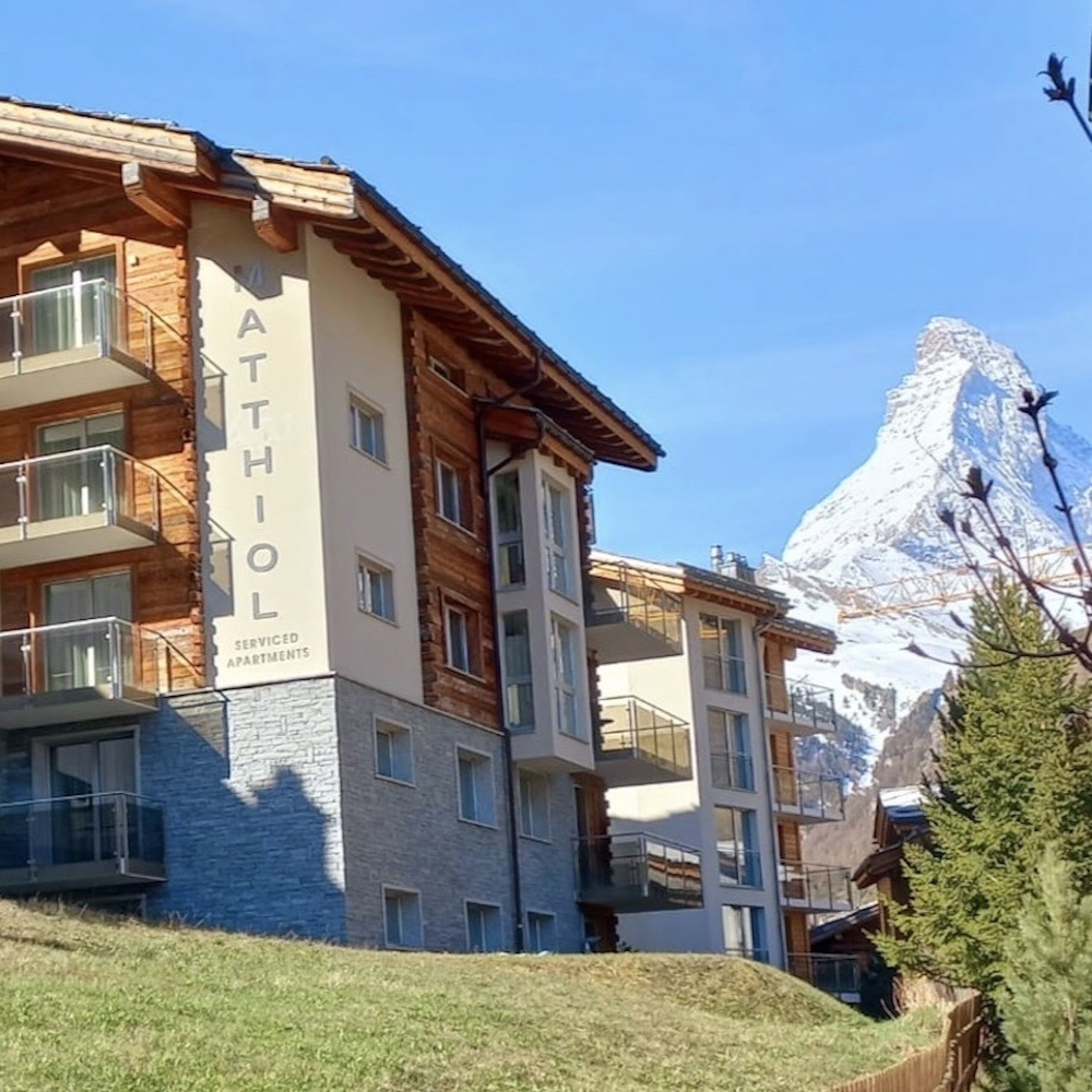 A multi-story building with a sign reading "ATHOL SERVICED APARTMENTS" and a mountain in the background.