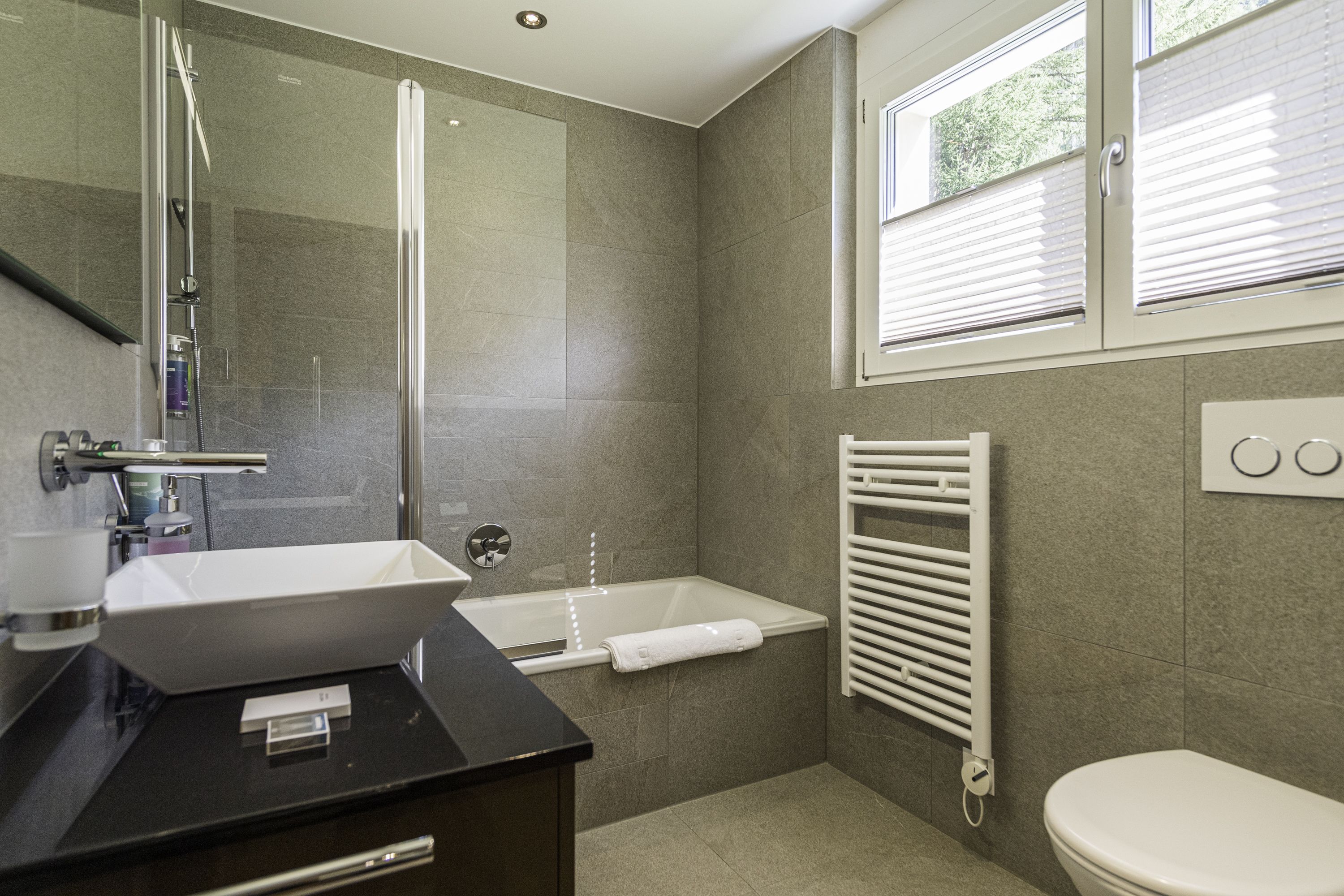 Un baño moderno con ducha de vidrio, lavamanos blanco, bañera y retrete.