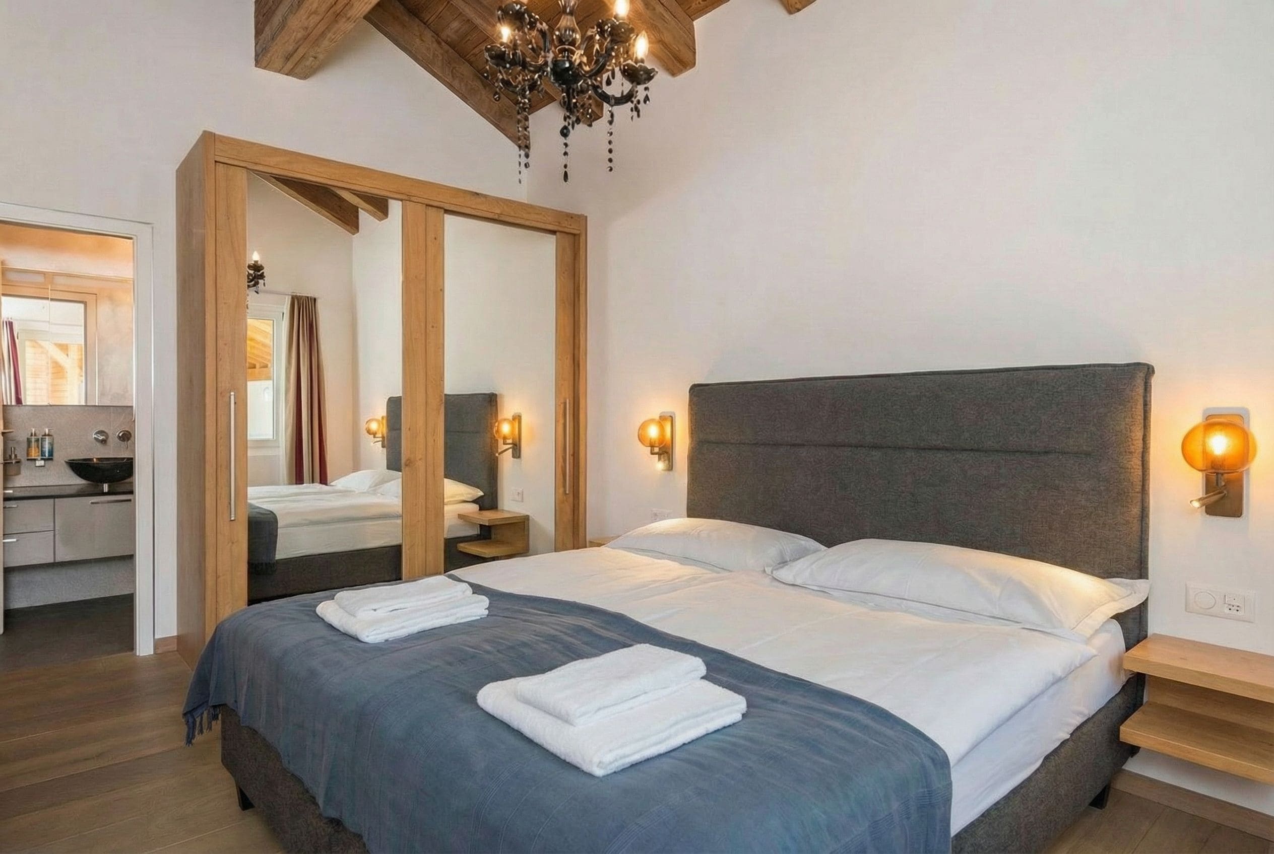 Un dormitorio moderno con una cama grande, cabecera de madera y lámparas de noche.