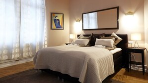 A bedroom with a bed, bedside lamps, a large mirror, and a chandelier. - Urban Flats Vienna City Center (Vienna)
