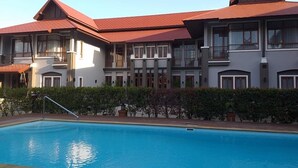 Un hôtel doté d’une piscine, de plusieurs balcons et d’un toit rouge.