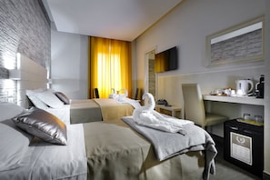 A hotel room with two beds, a desk, a chair, a television, and a minibar. - Vatican Relax (Rome)