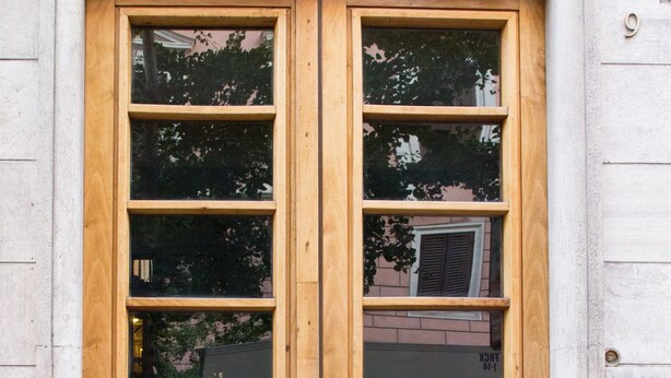 Puerta doble de madera con paneles de vidrio y una placa de latón en la parte inferior.