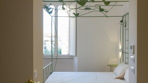 Un dormitorio con cama, ventana, planta verde y puerta.