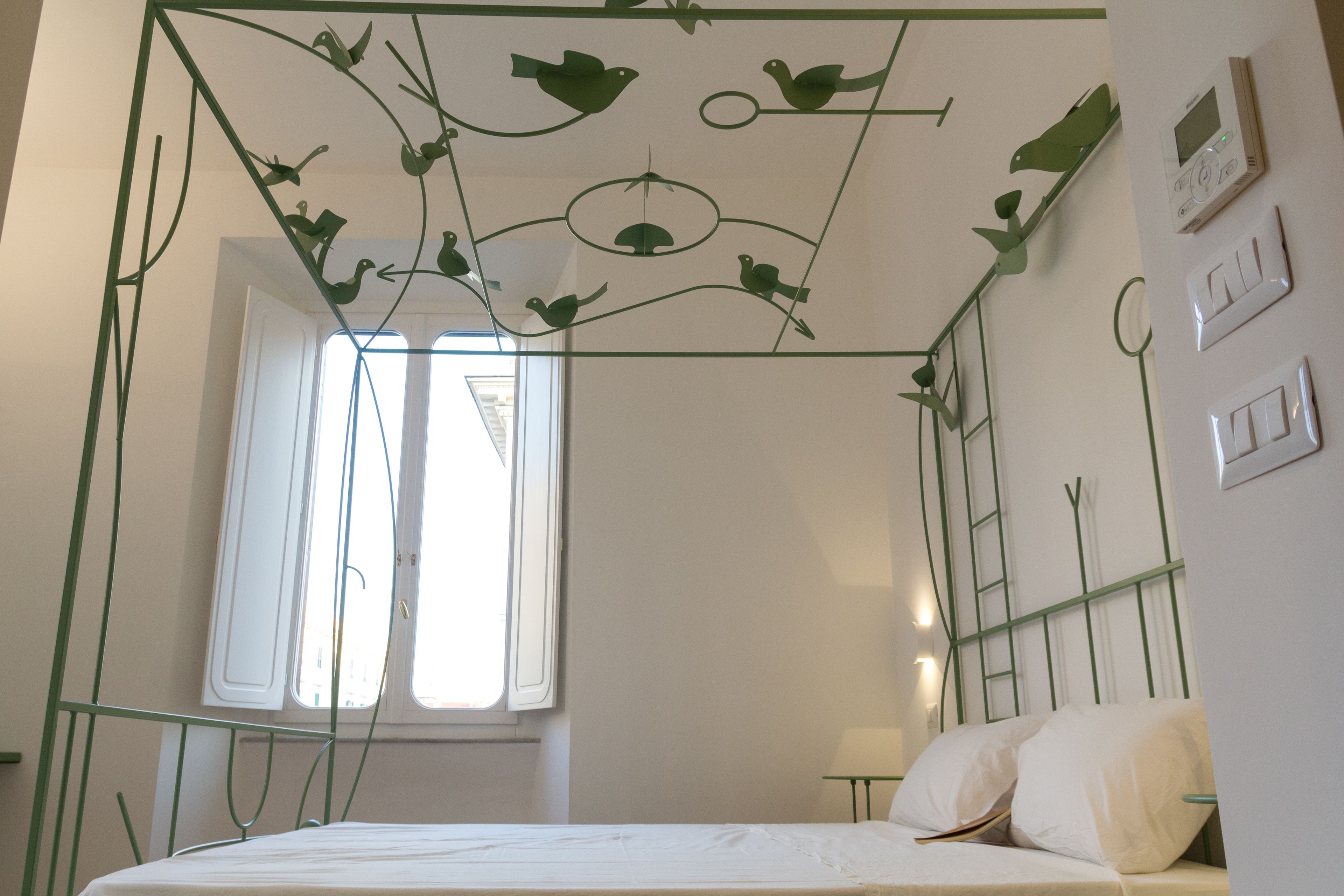 A bedroom with a bed, a window, and a wall-mounted light fixture.