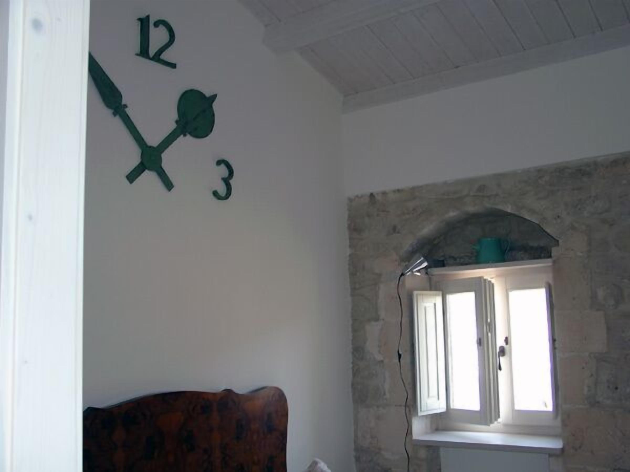 A room with a stone wall, a window with shutters, and a wooden headboard.