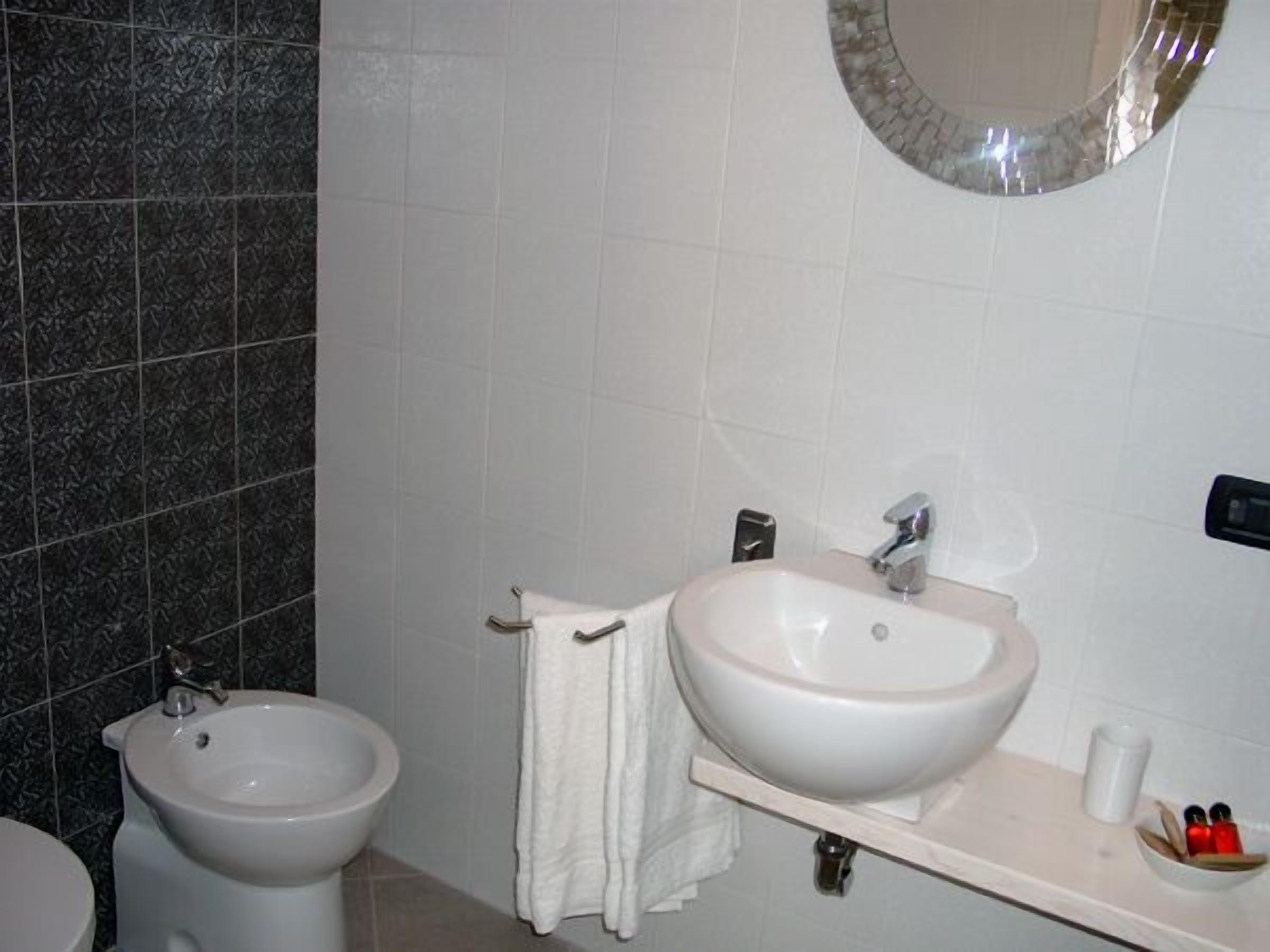 A bathroom with a bidet, a sink, and a mirror.