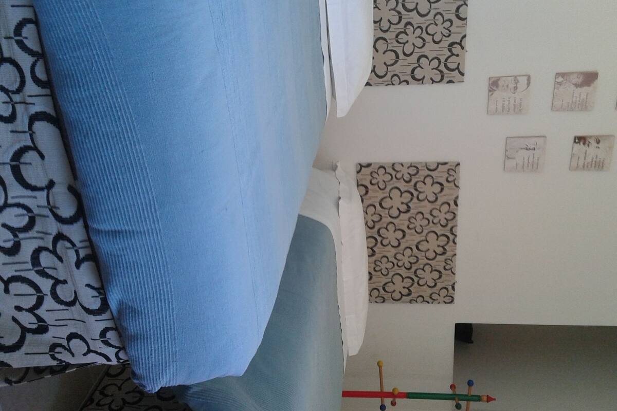 Une pièce avec des rideaux à motifs, un mur orné de tableaux encadrés et une fenêtre bien visible.