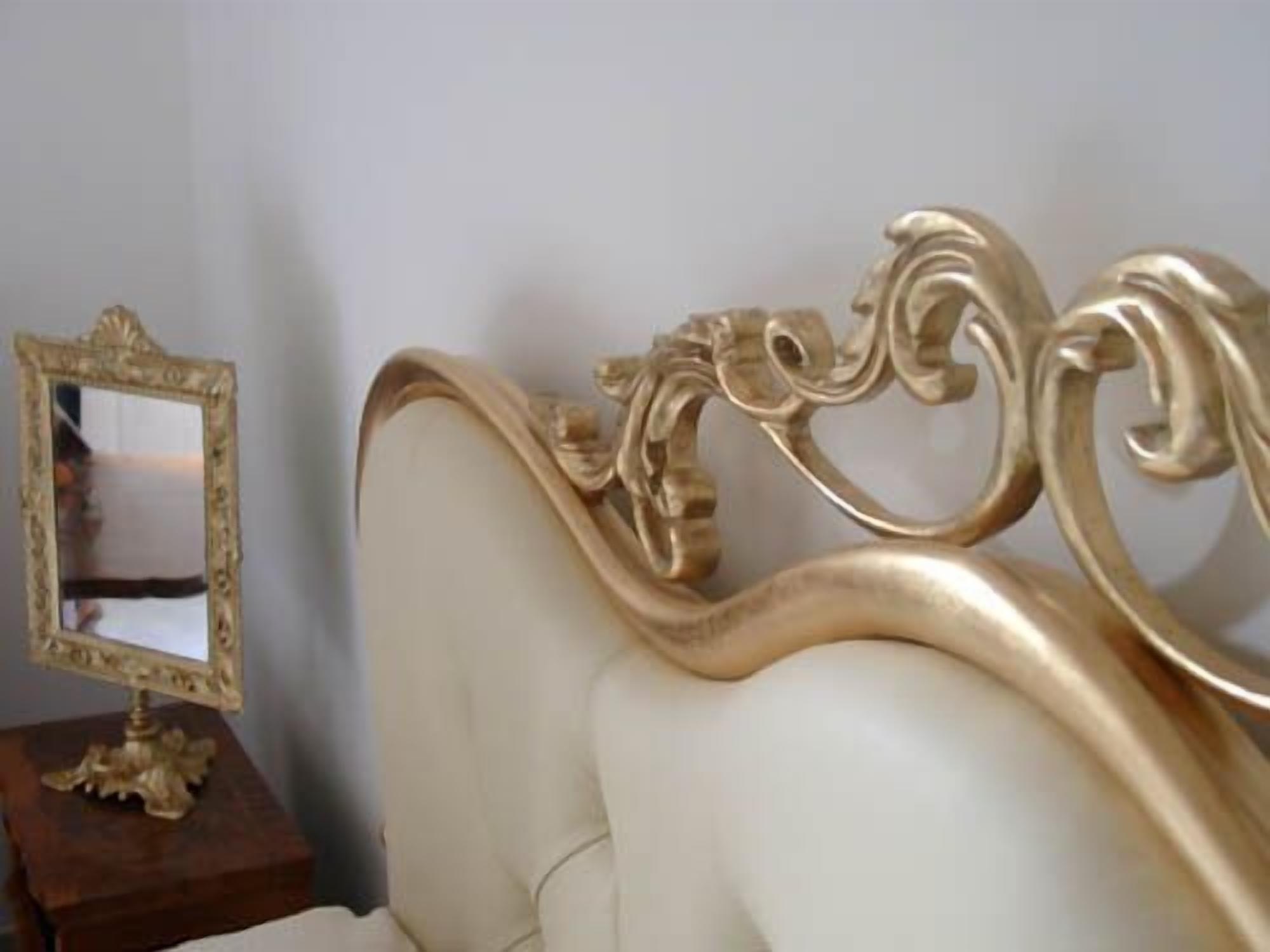 A bed with an ornate headboard and a mirror on a wooden side table.