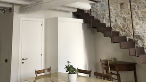Een eetruimte met een marmeren tafel, houten stoelen, een kroonluchter en een trap met stenen muren.