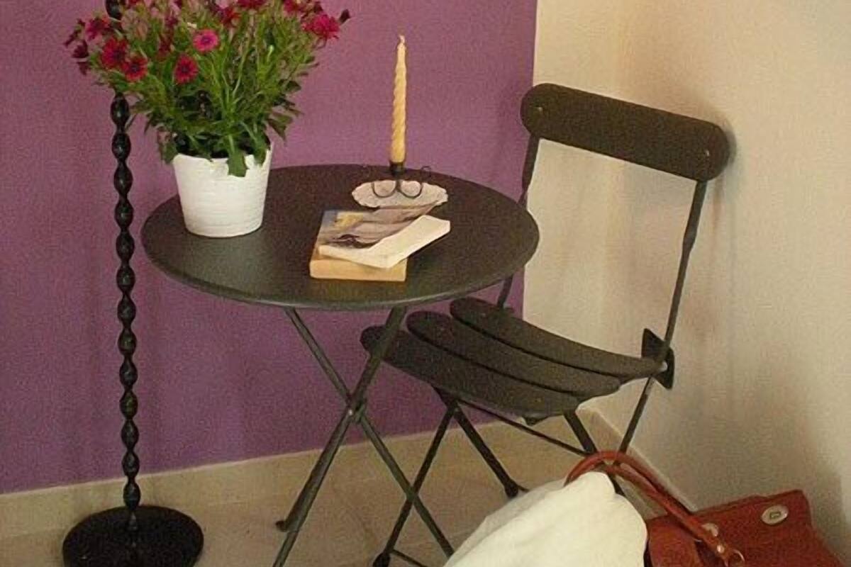 Une petite table avec une lampe, une plante en pot et une bougie.