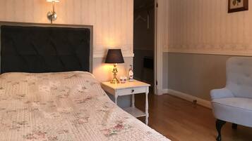 A bedroom with a bed, bedside lamp, dresser, chair, and a door leading to a closet.