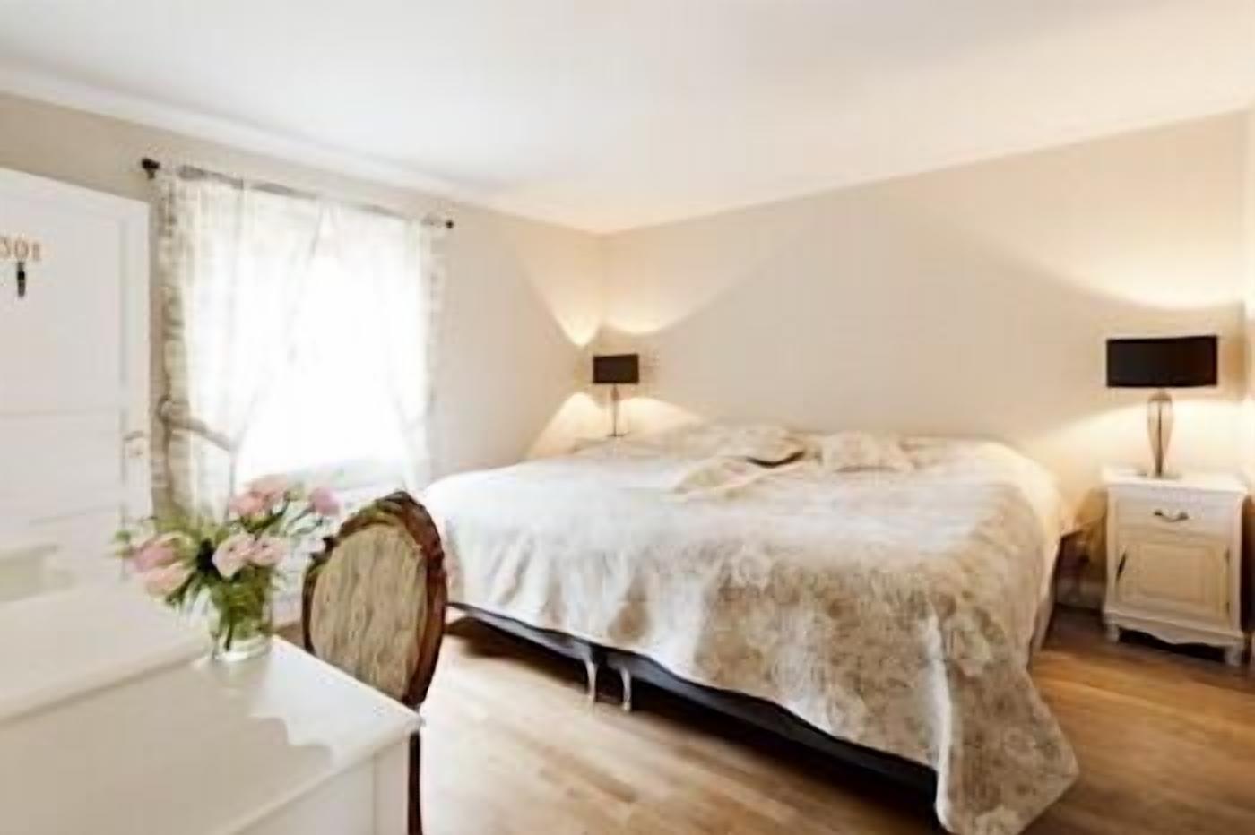 Un dormitorio con cama, mesitas de noche, un escritorio y una silla.