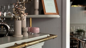 A kitchen counter with a white marble top, a gold-colored bar, and a potted plant with white flowers. - Hotell Gillet i Köping (Köping)